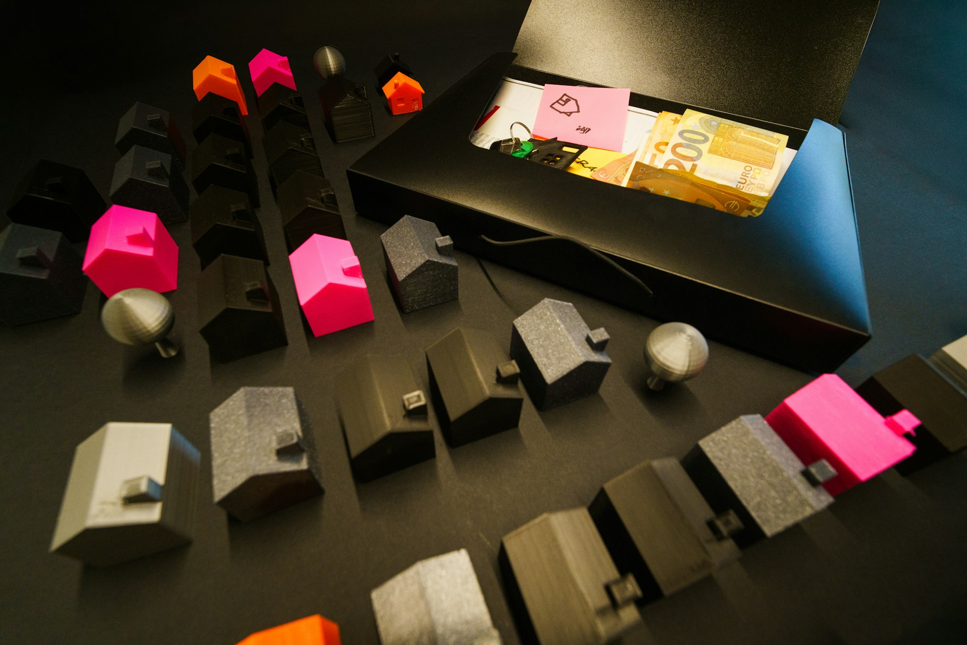 Miniature houses arranged with cash in an open box.